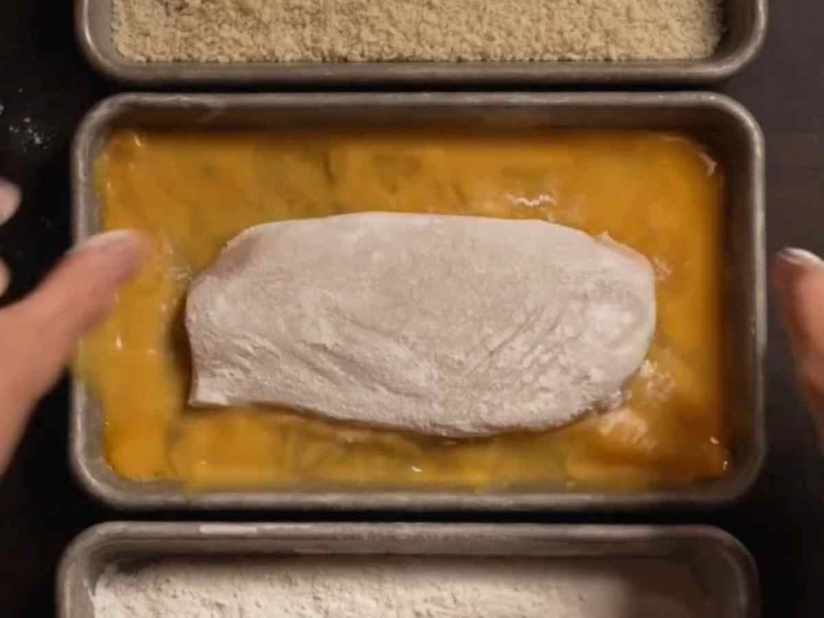O prato japonês que não é sushi e que virou o novo vício das minhas amigas #135 - Mão empanando os peitos de frango na farinha panko crocante para fritar.