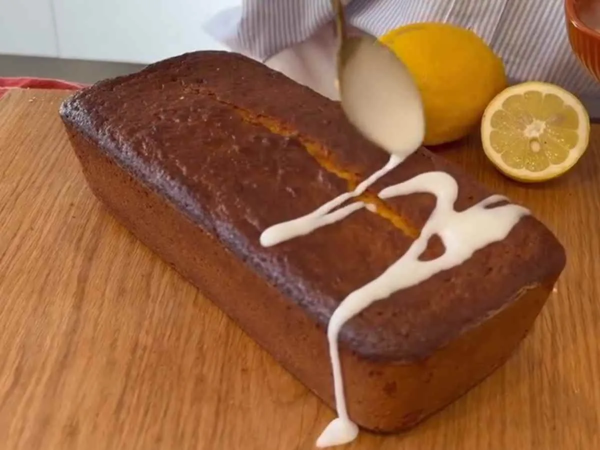 Chega de bolo seco! O método do limão fervido que salvou minha dieta sem glúten e sem lactose #126 Passo 3 da Receita de Bolo de Limão - Glacê branco sendo derramado sobre a racha central do bolo úmido.